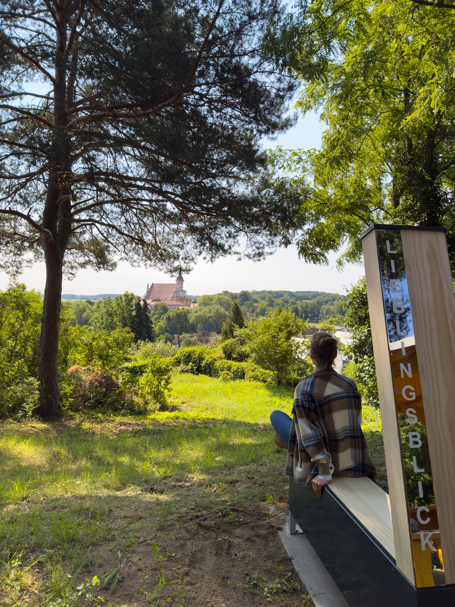 Frau von hinten zu sehen, sitzt auf dem "Lieblingsblick" mit Blick auf Neuzelle