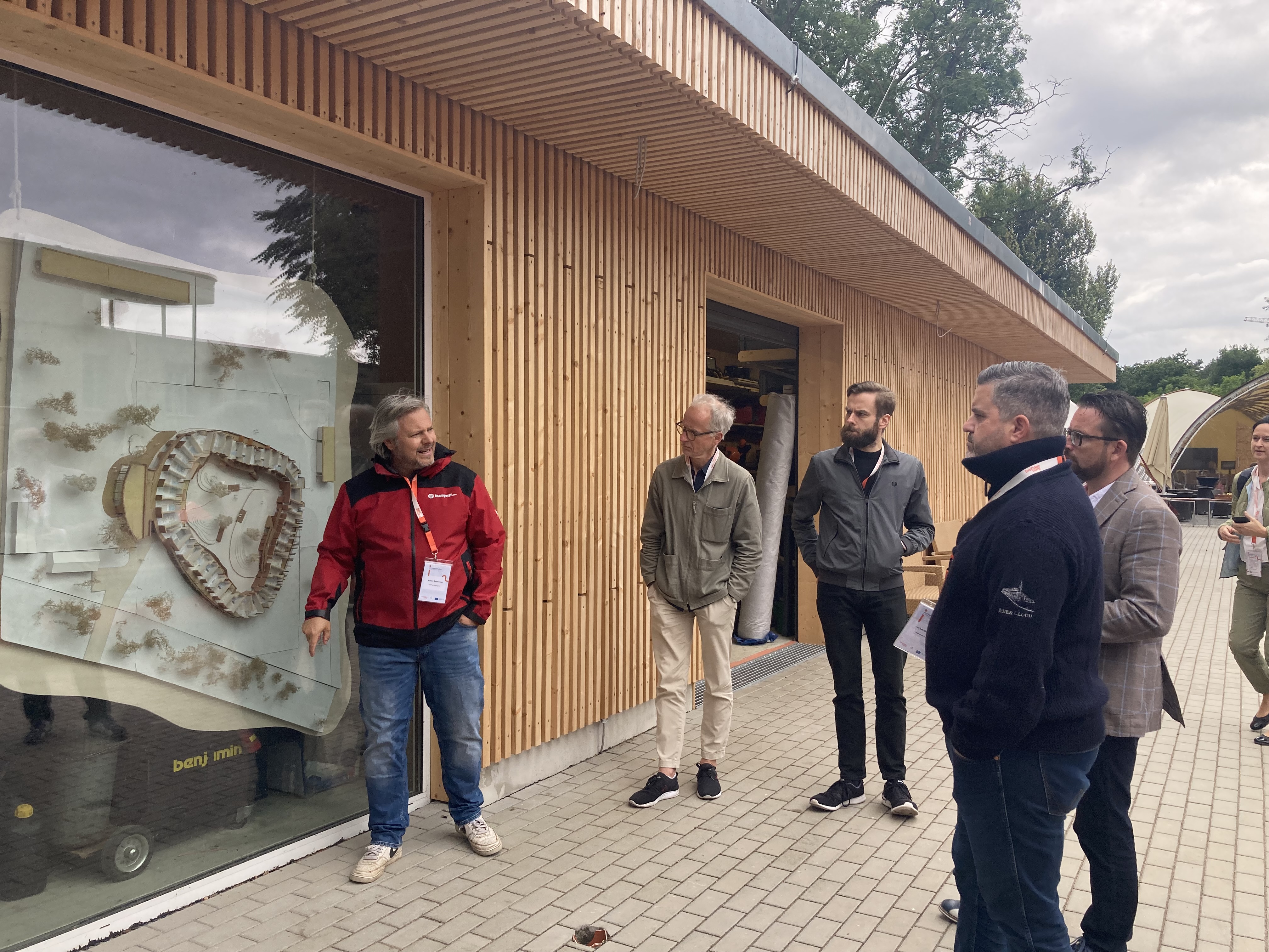 Dome 360° teamgeist - Aaron Backhaus steht vor Bootshaus und erklärt das Modell des neuen Resorts