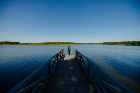 Auszeit am Ruppiner See_Frau steht auf einem Steg und blickt auf den See