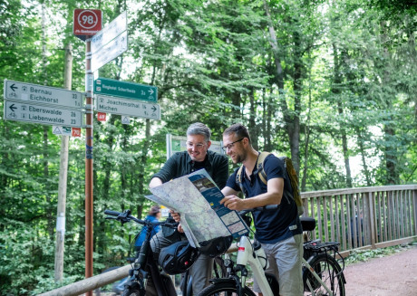 Zwei Radfahrer stehen unter einem Schild der Knotenwegweisung