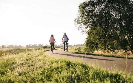 Ein weiblicher und ein männlicher Radfahrer auf einem Radweg zwischen Feldern im Sommer unterwegs