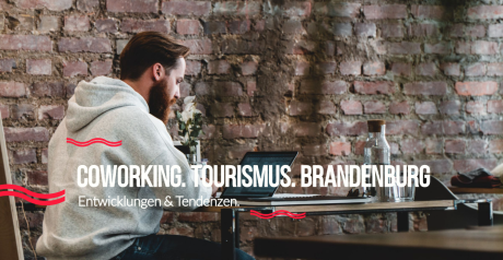 Foto von einem Mann am Laptop, der vor einer Backsteinwand sitzt