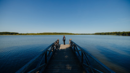 Auszeit am Ruppiner See_Frau steht auf einem Steg und blickt auf den See