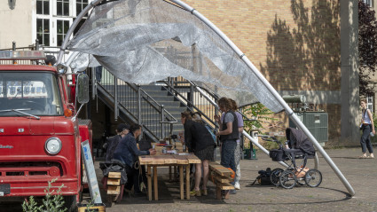 Besuchende nehmen an Tischen vor dem Feuerwehr-Truck Platz