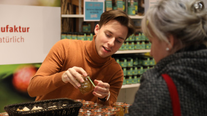 Junger Mann zeigt Frau ein Produkt am Messestand