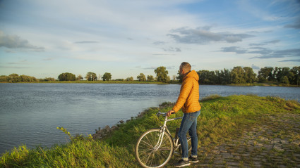 Radfahrer steht am Ufer und blickt auf die Elbe
