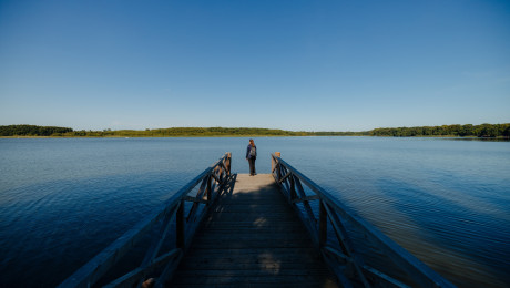Auszeit am Ruppiner See_Frau steht auf einem Steg und blickt auf den See