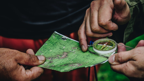 Foto von einem Landkartenausschnitt mit Kompass gehalten von zwei Händen