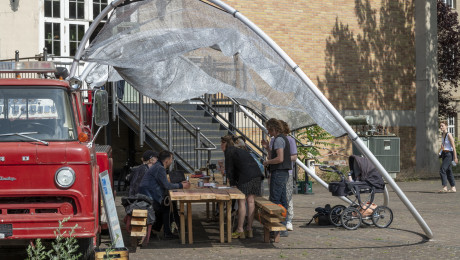 Besuchende nehmen an Tischen vor dem Feuerwehr-Truck Platz
