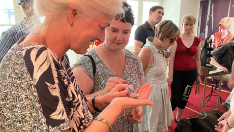 blinde Frau tastet einen Keramikvogel ab