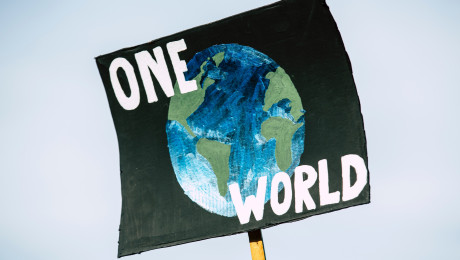 Plakat mit gemalter Weltkugel und Aufschrift "One World"