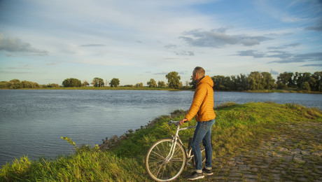 Radfahrer steht am Ufer und blickt auf die Elbe
