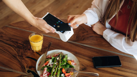 Junge Frau bezahlt am Café Tisch mit Kreditkarte