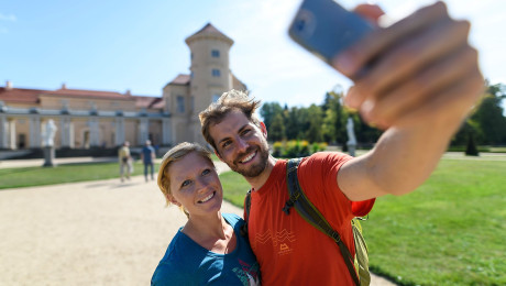 Zwei Spaziergänger machen Selfie vor dem Schloss Rheinsberg