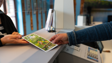 Ein Prospekt wird in der Touristinformation über den Counter gereicht.