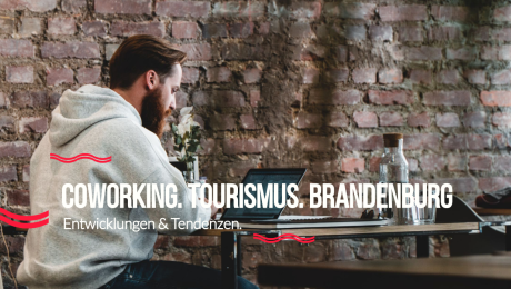 Foto von einem Mann am Laptop, der vor einer Backsteinwand sitzt